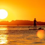 SUP nel delta del Po. ragazzo in piedi sul sup, sul mare al tramonto.