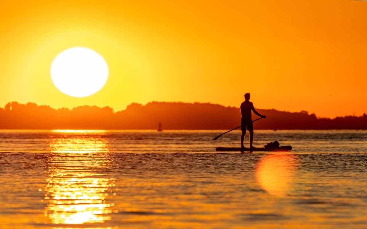 SUP nel delta del Po. ragazzo in piedi sul sup, sul mare al tramonto.
