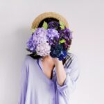 festa della donna. Dona in lilla con mazzo di fiori davanti al viso.