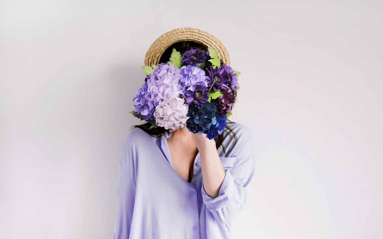 festa della donna. Dona in lilla con mazzo di fiori davanti al viso.