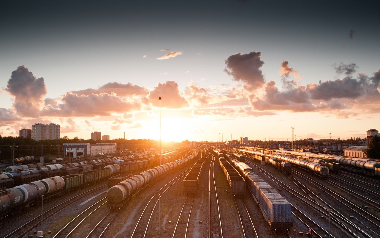 Partenze e viaggi: il punto della situazione. Treni in arrivo sui binari; tramonto