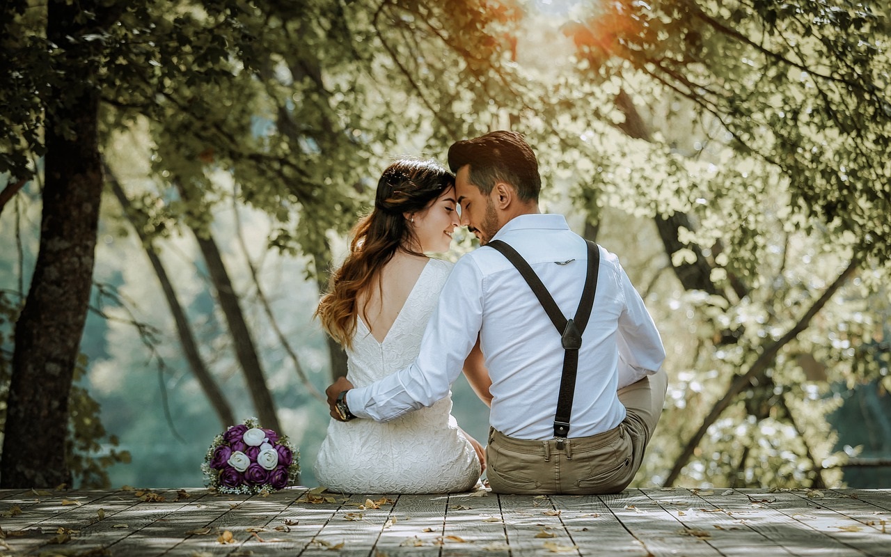 Sposarsi all'estero: le cerimonie. Due sposi si abbracciano seduti su un pontile.