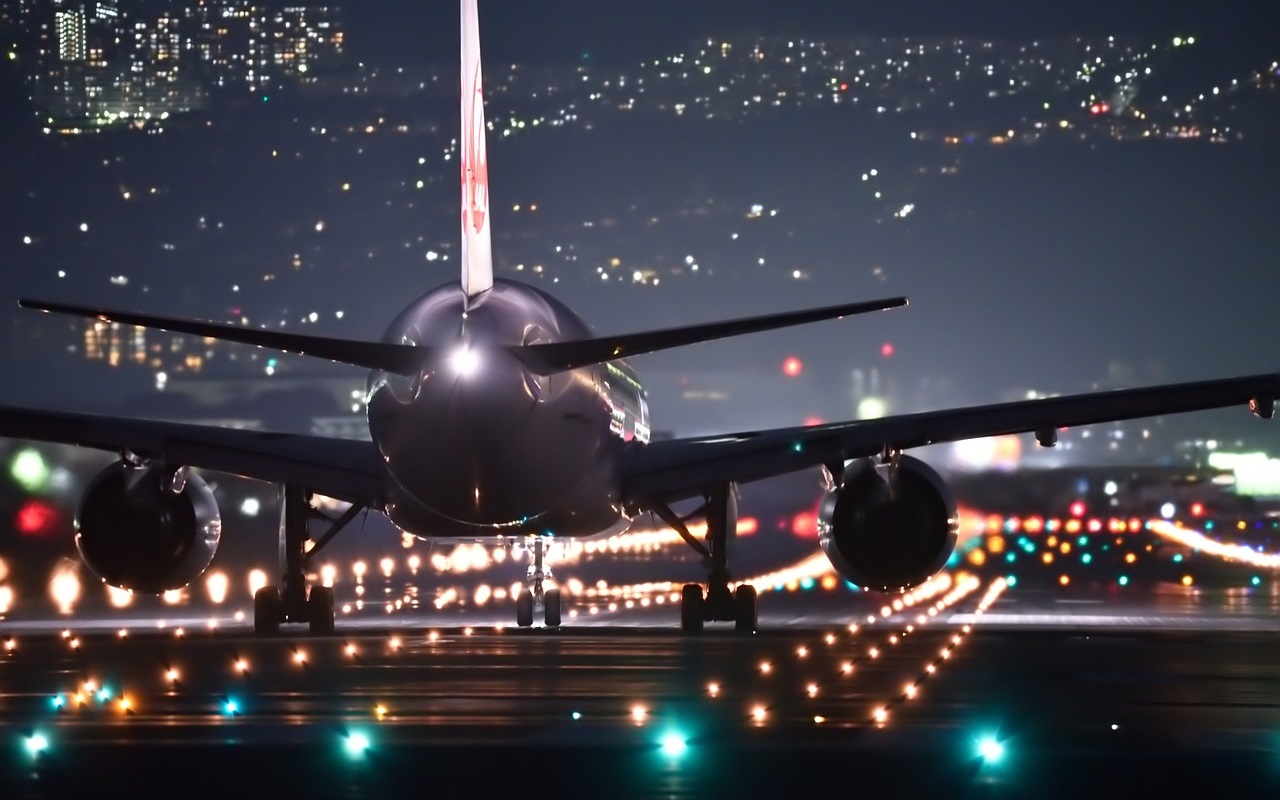 Aeroporti nel caos. Aereo in pista, di notte, pronto a decollare.