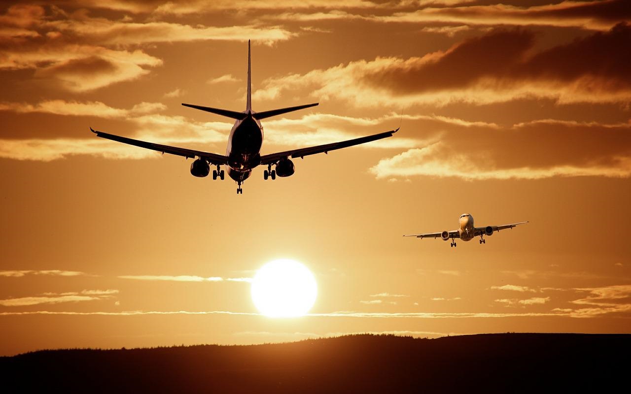Aeroporti nel caos. Due aerei volano in cielo al tramonto.