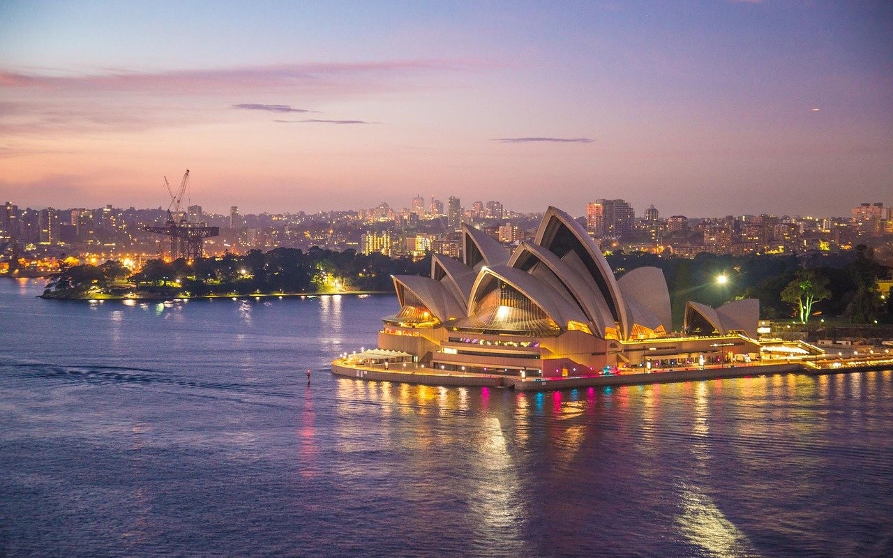 Australia. Fine del certificato verde. Vista sulla Sydney opera house circondata dal mare e dalla città sullo sfondo.