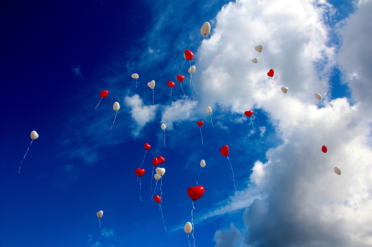 Viaggi di nozze; la ripartenza. palloncini rossi e bianchi in un cielo azzurro con nuvole.