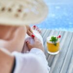 Viaggi di lusso: Belmond Hotel. Donna a bordo piscina con drink.