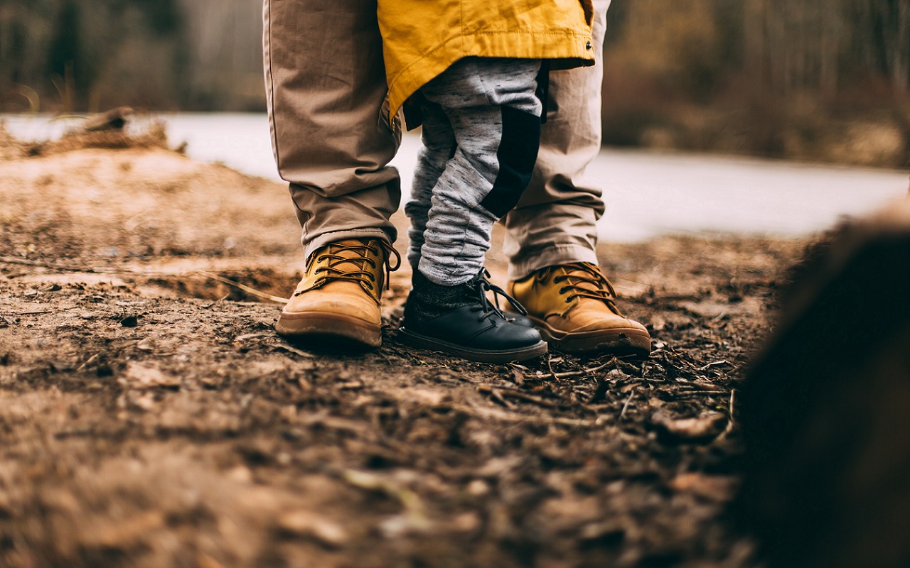 Cosa regalare alla festa del papà? Piedi di bimbo e del suo papà che giocano all'aperto.