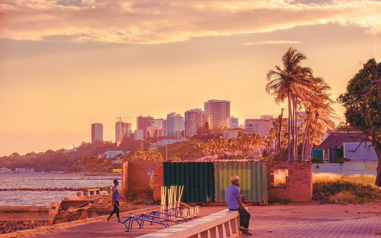 Alla scoperta del Mozambico 2023. Vista di Maputo al tramonto, un signore siede su un muro.