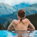 L'infinity pool di Singapore. Ragazza di spalle in una piscina a sfioro. Davanti, le montagne.