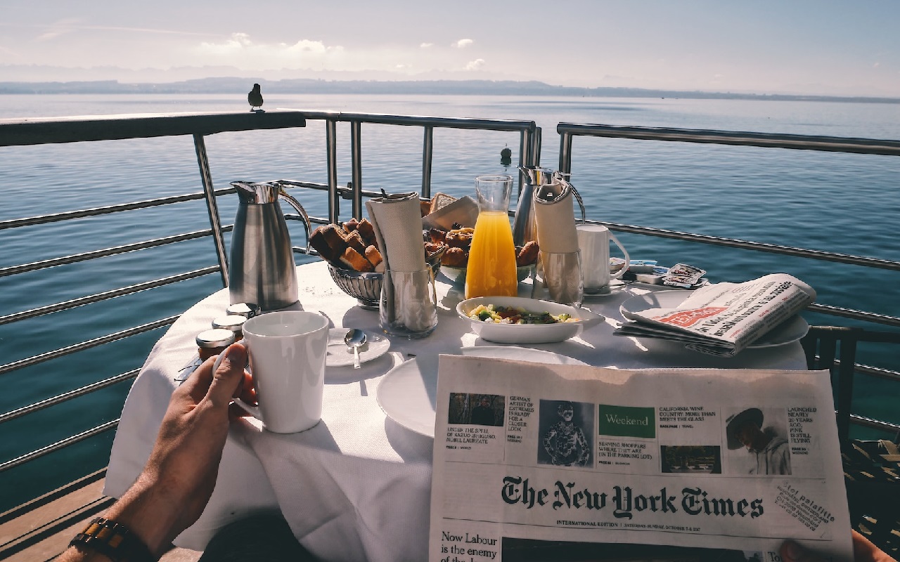 Crociere di lusso 2024. Colazione in terrazzo a bordo nave, leggendo il New York Times.